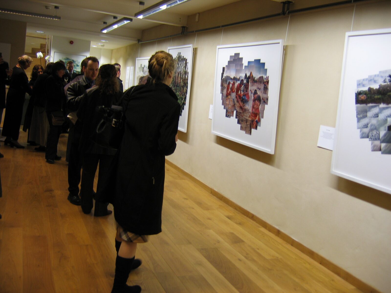 Gallery opening with visitors viewing photo collage works