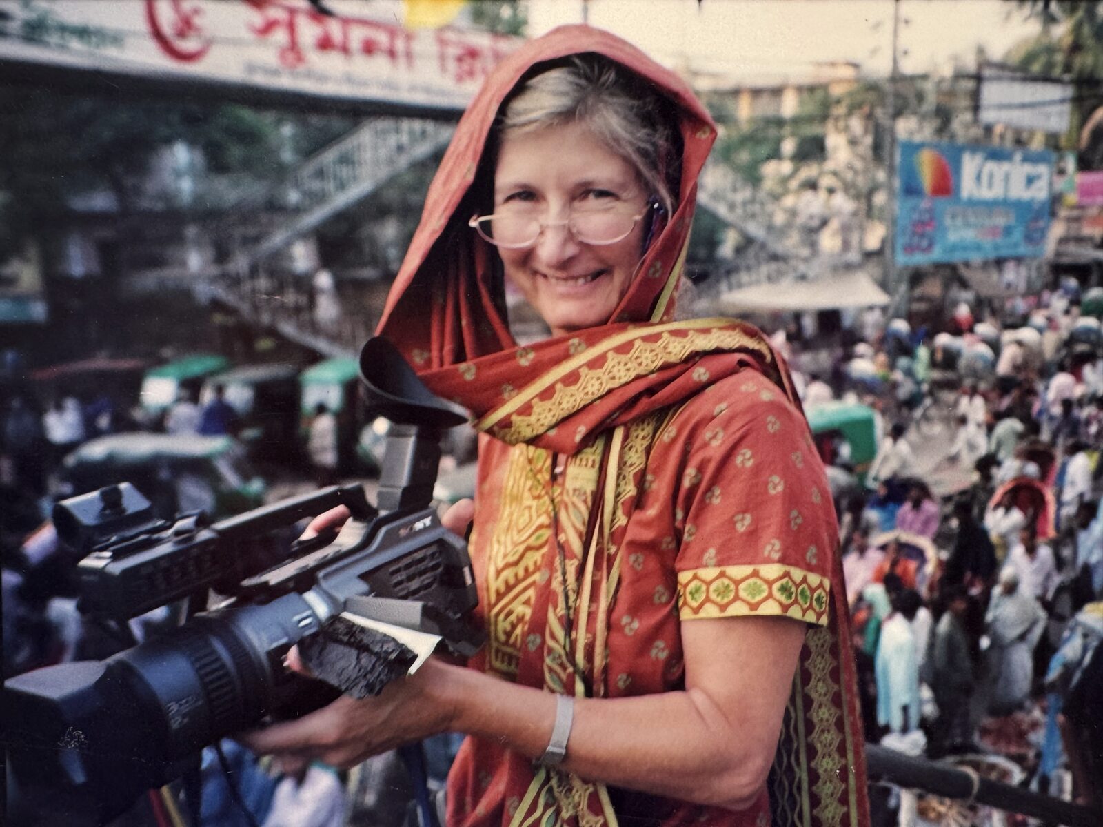 Christine filming with a video camera on a busy South Asian street